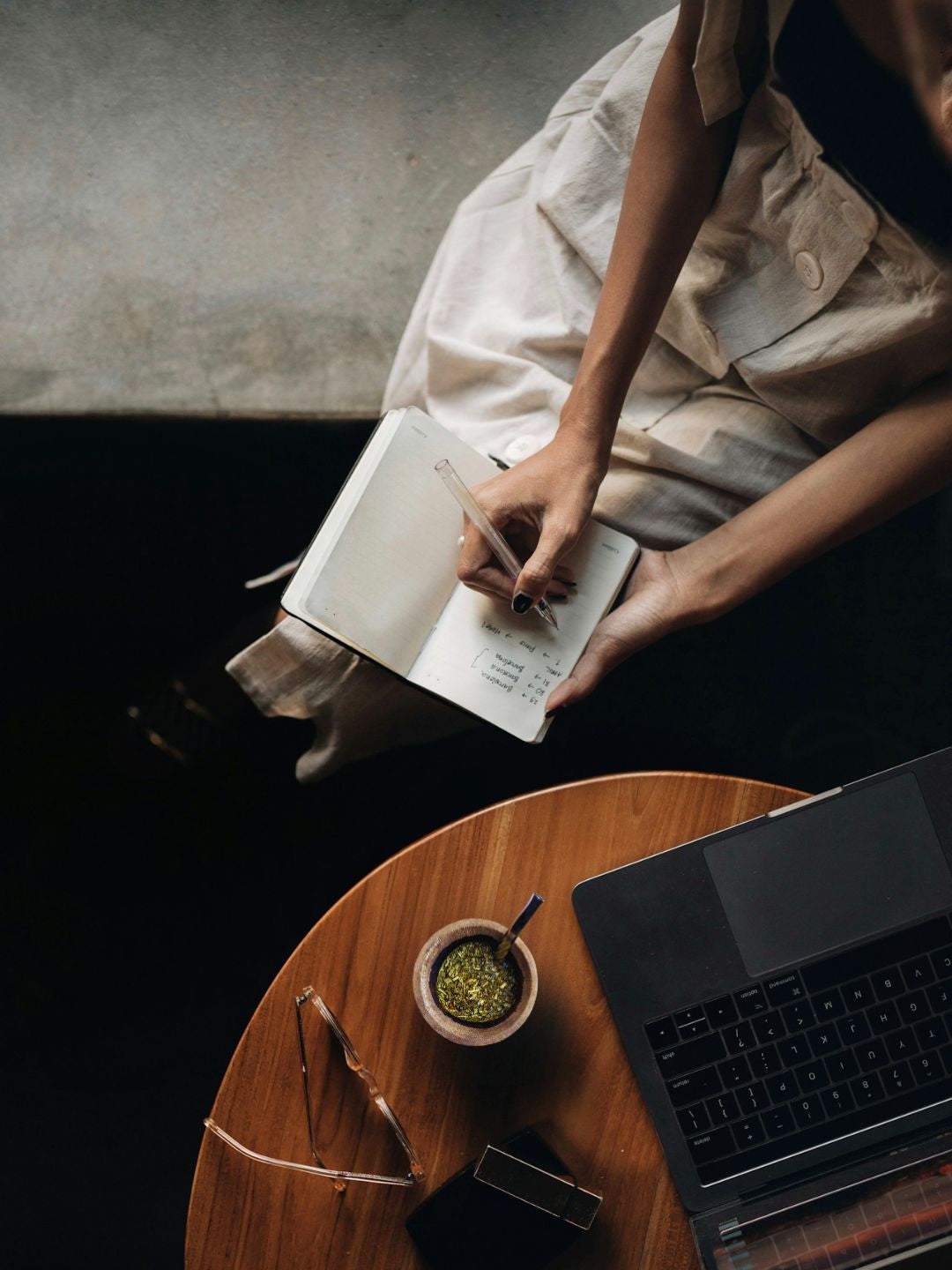Woman writing in notebook beside a yerba maté gourd, yerba maté vs coffee for creative focus
